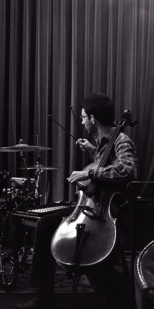 Daniel Klein playing
	 glockenspiel while holding a cello at the 2013-04-23
	 Passionate Mammals show at Dusk, in Providence, RI.